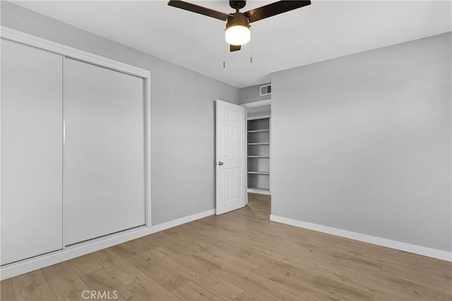 unfurnished bedroom featuring visible vents, baseboards, wood finished floors, and a closet
