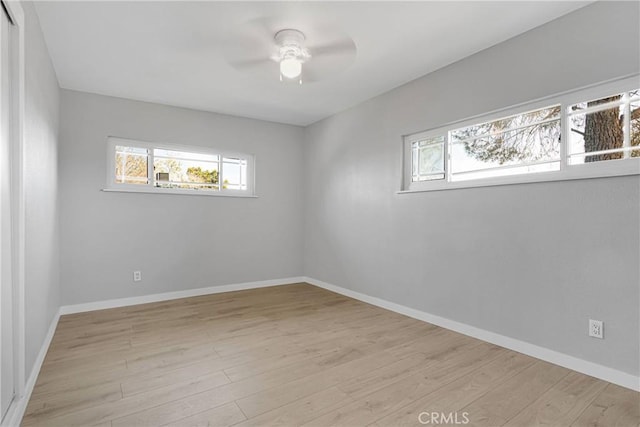 spare room with a ceiling fan, baseboards, a healthy amount of sunlight, and wood finished floors