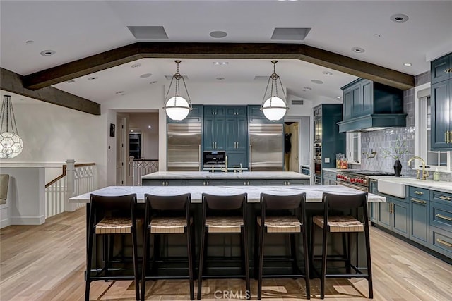 528 15th St, Manhattan Beach, CA 90266 - kitchen with wall chimney range hood, tasteful backsplash, an island with sink, high quality appliances, and blue cabinets