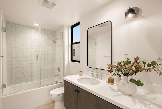 full bathroom featuring bath / shower combo with glass door, vanity, visible vents, and toilet