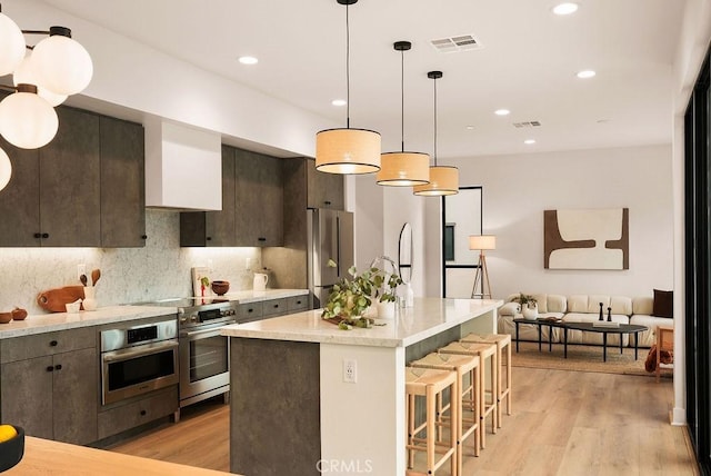 kitchen with a kitchen bar, light wood-type flooring, visible vents, and stainless steel appliances