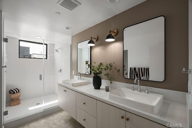 full bath featuring a stall shower, double vanity, a sink, and visible vents