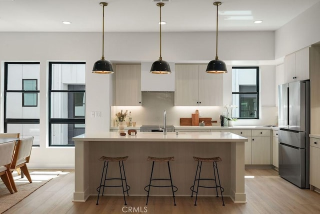 kitchen featuring light wood finished floors, a sink, freestanding refrigerator, and light countertops