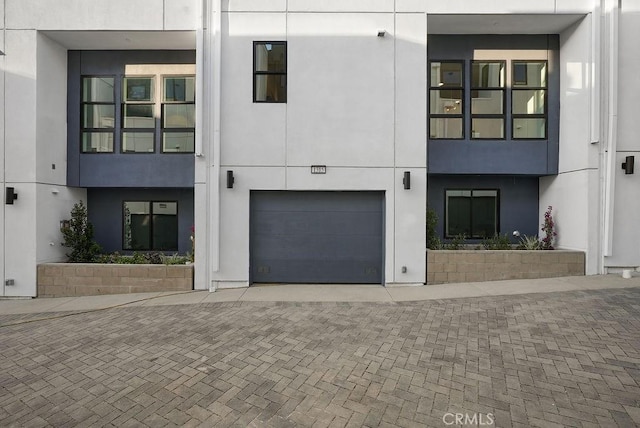 view of front of home with a garage, stucco siding, and decorative driveway