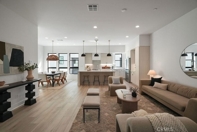 living room with visible vents, recessed lighting, and light wood-style floors