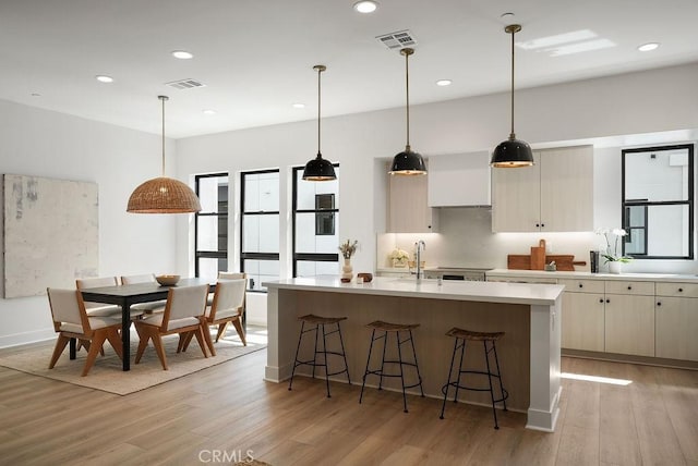 kitchen with visible vents, light countertops, light wood-type flooring, and a kitchen breakfast bar