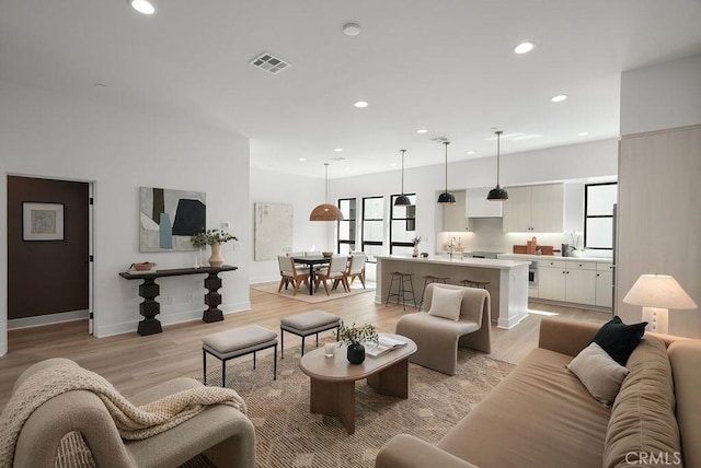living room with light wood-style floors, recessed lighting, visible vents, and baseboards