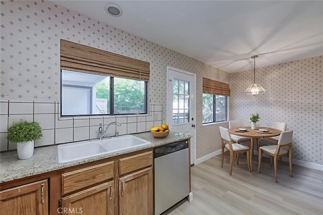 4837 N Hulbert Ave, Fresno, CA 93705 - kitchen with stainless steel dishwasher, wallpapered walls, light wood-type flooring, brown cabinets, and pendant lighting