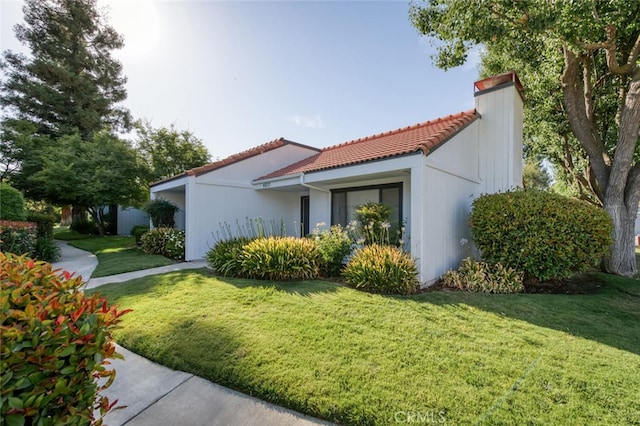 4837 N Hulbert Ave, Fresno, CA 93705 - view of side of home featuring a tile roof, a lawn, and a chimney