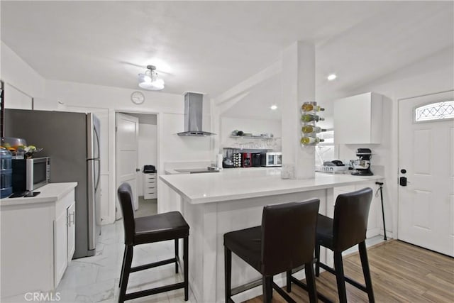 12152 Rosecrans Ave, Norwalk, CA 90650 - kitchen with wall chimney range hood, a kitchen bar, white cabinets, appliances with stainless steel finishes, and light countertops