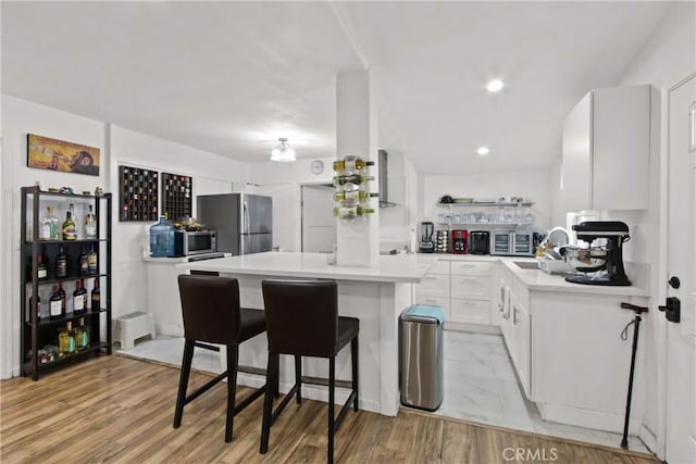 12152 Rosecrans Ave, Norwalk, CA 90650 - kitchen with appliances with stainless steel finishes, a kitchen island, light countertops, white cabinetry, and a breakfast bar area
