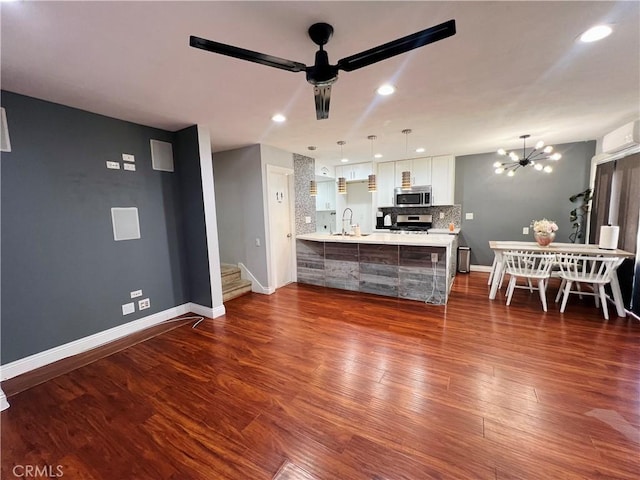 17760 Palo Verde Ave Unit 27, Cerritos, CA 90703 - living room with baseboards, dark wood-style floors, ceiling fan with notable chandelier, and a wall unit AC