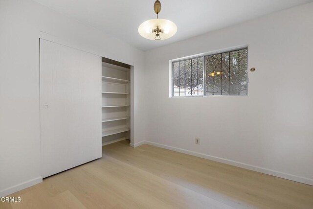 unfurnished bedroom with baseboards, a closet, and wood finished floors