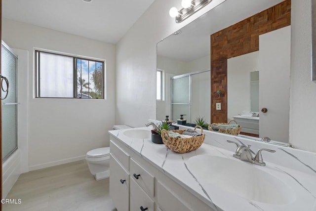 bathroom featuring double vanity, an enclosed shower, toilet, and a sink
