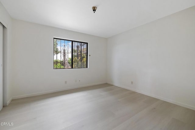 unfurnished room with baseboards and light wood-style flooring