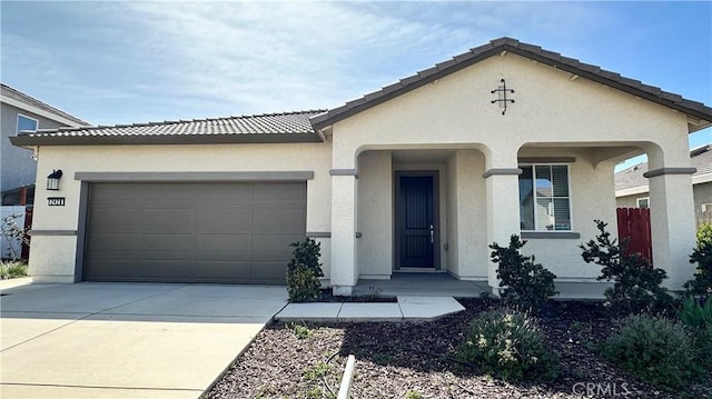 view of front of home with a tile roof, concrete driveway, stucco siding, and an attached garage
