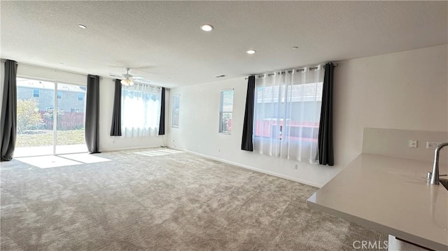 carpeted empty room with a ceiling fan, a textured ceiling, baseboards, visible vents, and recessed lighting