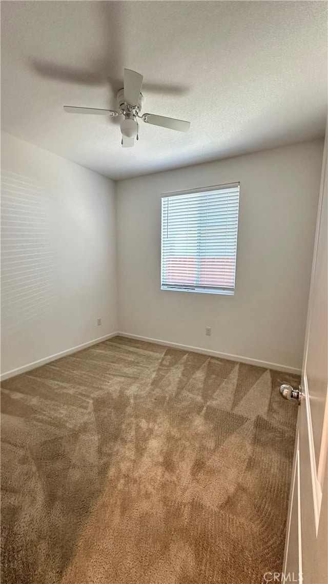 carpeted spare room with a textured ceiling, baseboards, and ceiling fan