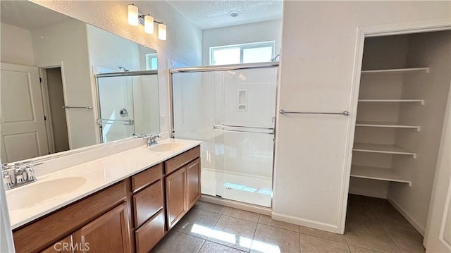 full bathroom featuring tile patterned floors, a sink, a stall shower, and a textured ceiling