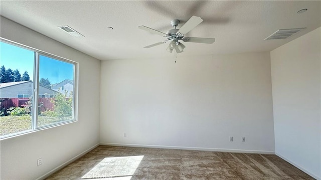 spare room with carpet, baseboards, ceiling fan, and visible vents
