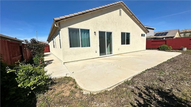 back of property with a fenced backyard, stucco siding, and a patio area