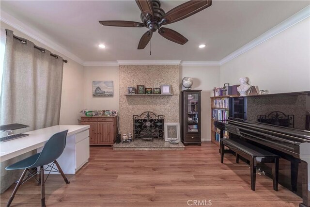 office area featuring ceiling fan, ornamental molding, light wood-style flooring, and a fireplace