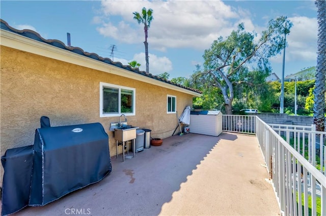 view of patio / terrace featuring fence, an outbuilding, a grill, and a shed