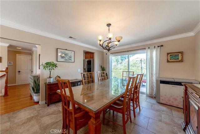 dining room with crown molding, baseboards, a chandelier, and visible vents