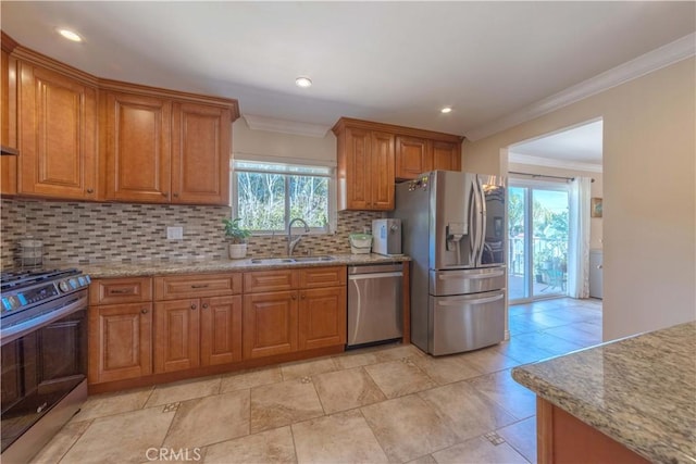 kitchen with decorative backsplash, appliances with stainless steel finishes, brown cabinets, a sink, and ornamental molding