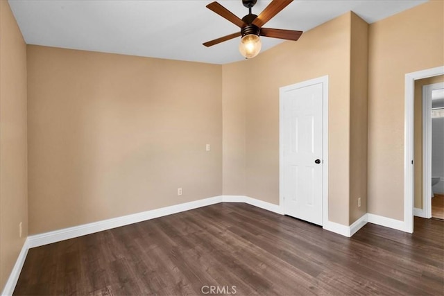 spare room featuring a ceiling fan, dark wood-type flooring, and baseboards