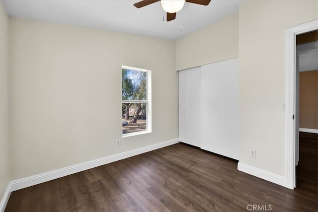 empty room with baseboards, dark wood-style flooring, and a ceiling fan