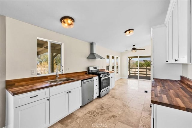 kitchen featuring a sink, wood counters, appliances with stainless steel finishes, and wall chimney exhaust hood