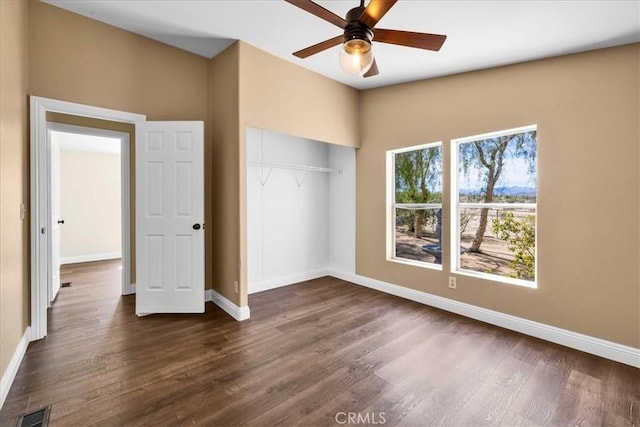 unfurnished bedroom with baseboards, visible vents, a closet, and dark wood-style flooring
