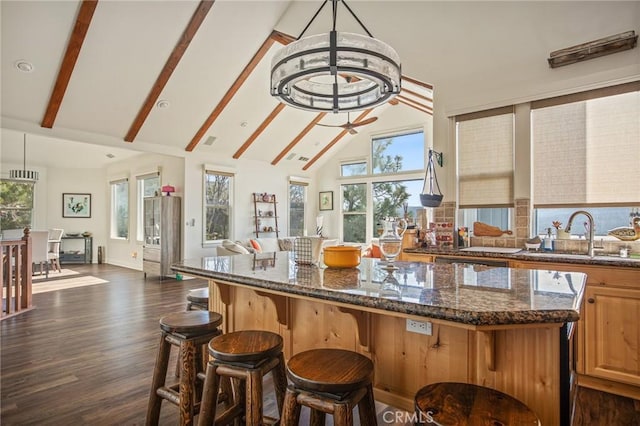 kitchen featuring a sink, dark wood-style flooring, open floor plan, beamed ceiling, and a kitchen island