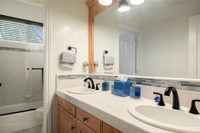 bathroom featuring shower / bath combination with glass door, toilet, a sink, and double vanity
