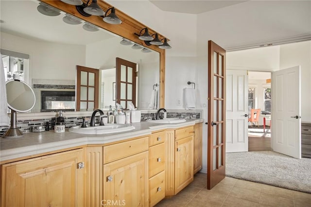 bathroom with tasteful backsplash, french doors, a sink, and double vanity