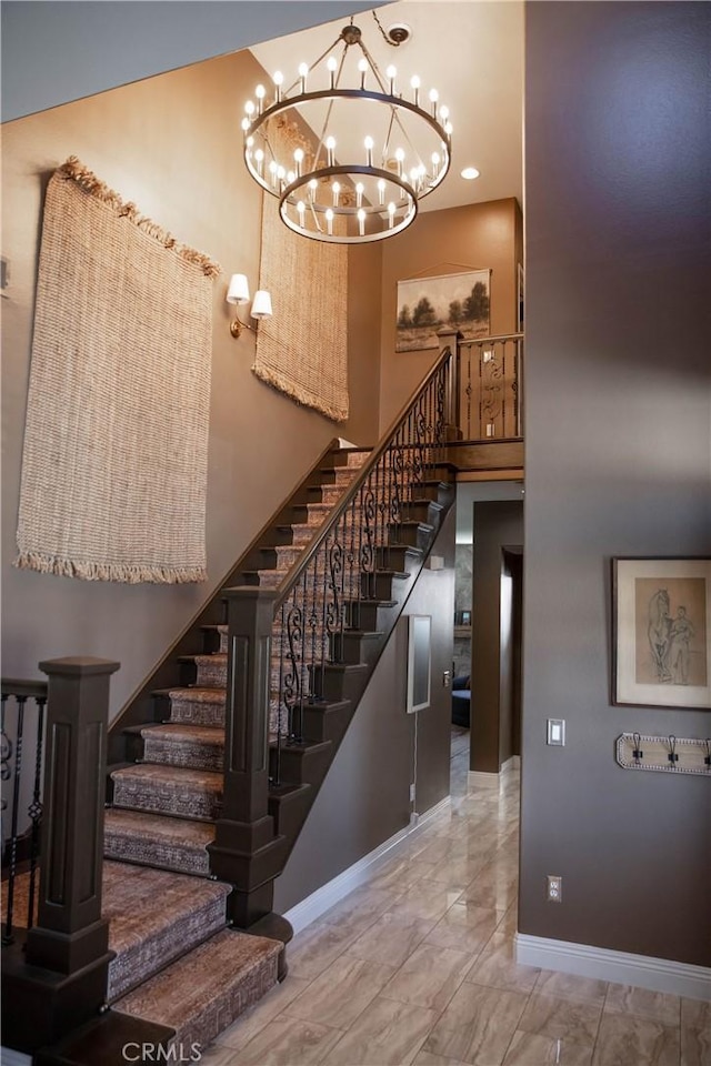 staircase featuring marble finish floor, baseboards, a high ceiling, and a chandelier