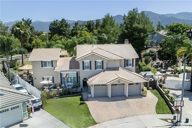 view of front of house with fence, a tiled roof, decorative driveway, a garage, and a mountain view