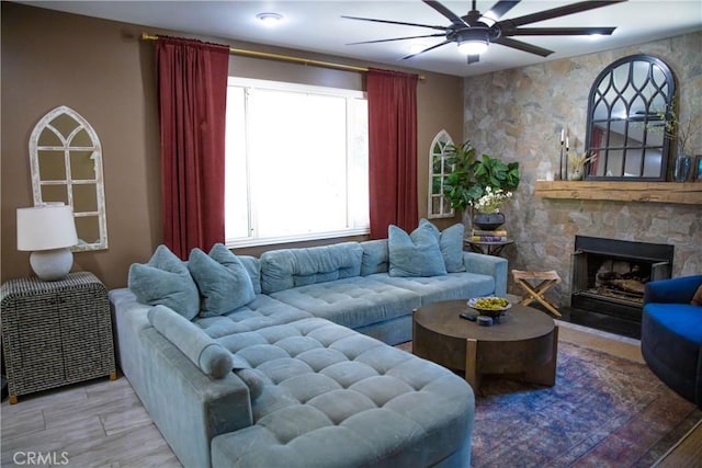 living area featuring a fireplace, wood finished floors, and a ceiling fan
