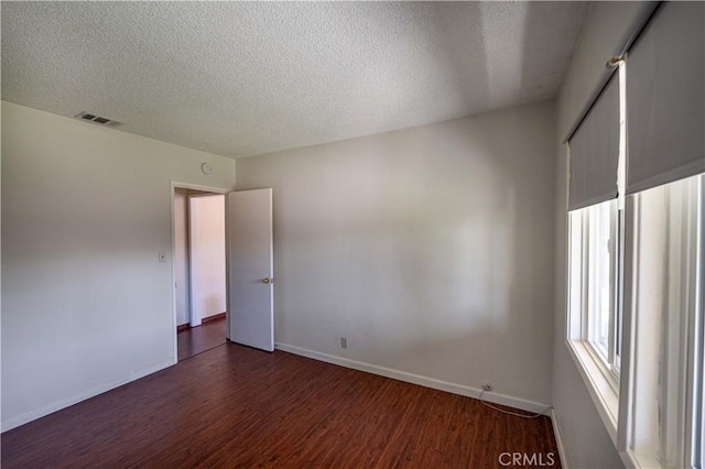 12821 Salisbury St, Baldwin Park, CA 91706 - empty room with visible vents, baseboards, a textured ceiling, and dark wood finished floors