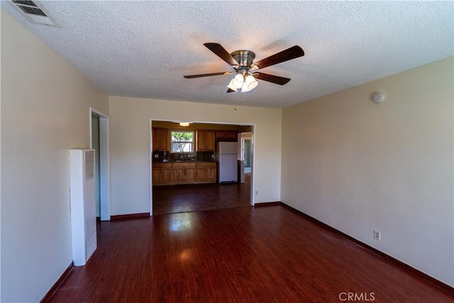 12821 Salisbury St, Baldwin Park, CA 91706 - unfurnished living room with dark wood-style flooring, a textured ceiling, visible vents, ceiling fan, and a sink
