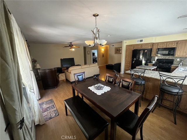 dining space featuring visible vents, a ceiling fan, and light wood finished floors