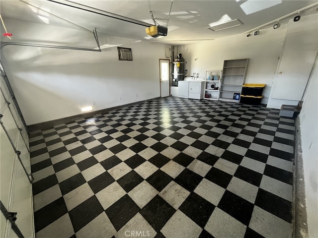 garage with baseboards, a garage door opener, water heater, and washer and dryer