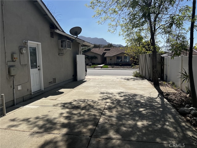 view of side of property featuring crawl space, fence, a mountain view, a patio, and stucco siding