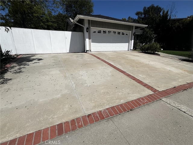 view of property exterior with concrete driveway, fence, board and batten siding, and a garage