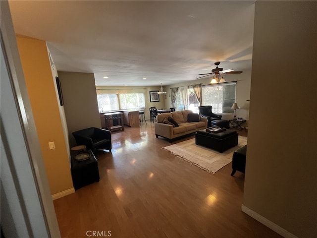 living room with baseboards, a ceiling fan, and wood finished floors