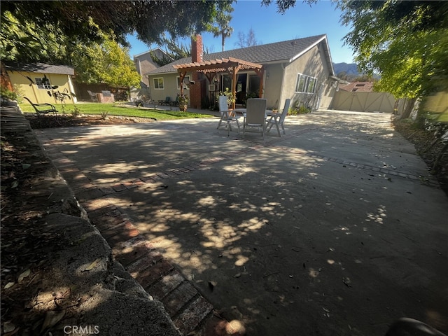 rear view of house featuring a pergola, a patio, stucco siding, a chimney, and a gate
