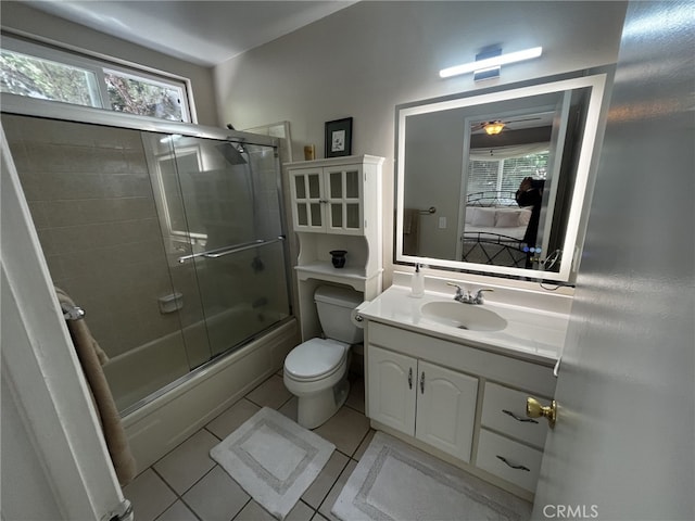 bathroom featuring tile patterned flooring, vanity, toilet, bath / shower combo with glass door, and a ceiling fan