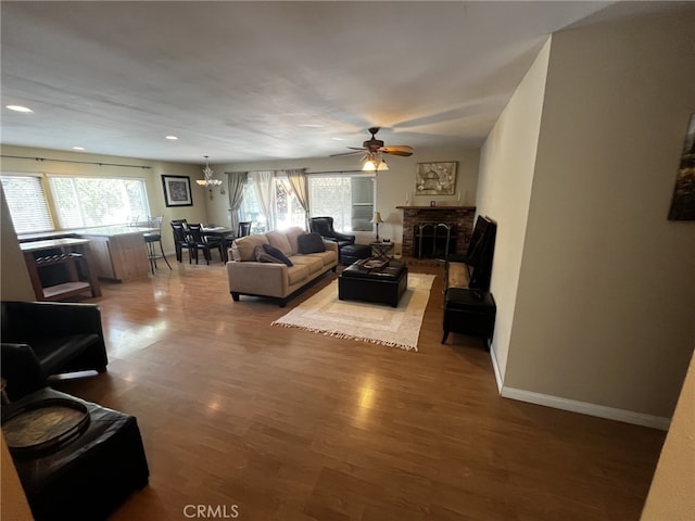 living room with ceiling fan, a brick fireplace, wood finished floors, baseboards, and recessed lighting