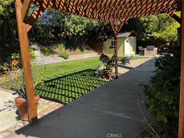 view of patio / terrace with fence, a storage unit, an outbuilding, and a pergola